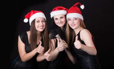 Girls with Santa Claus hats singing Christmas songs